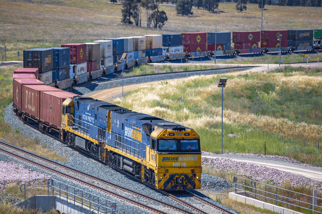 A Pacific National freight train carrying container cargo on rail tracks in rural Australia