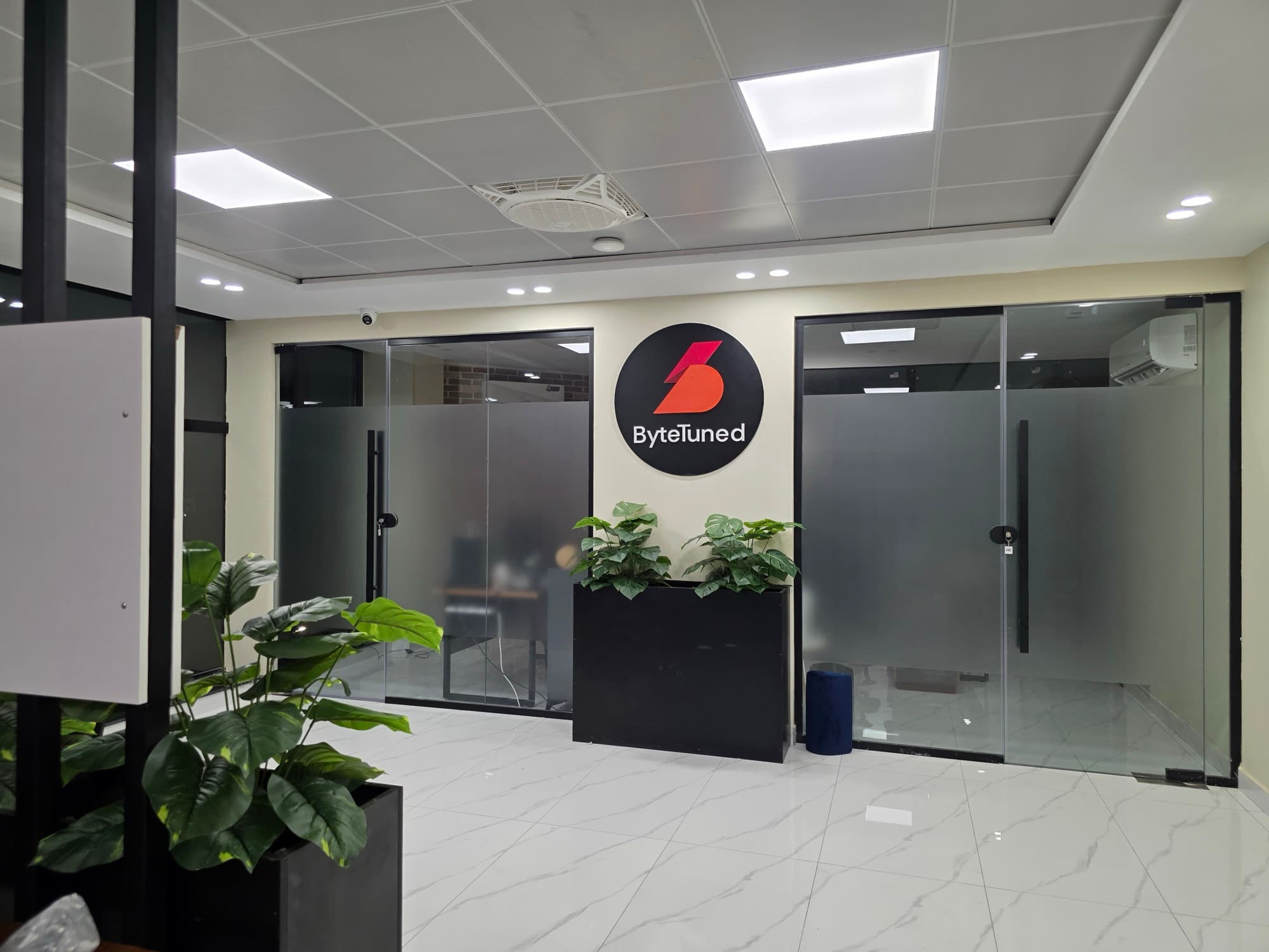 ByteTuned office reception with the branded logo wall and glass meeting rooms