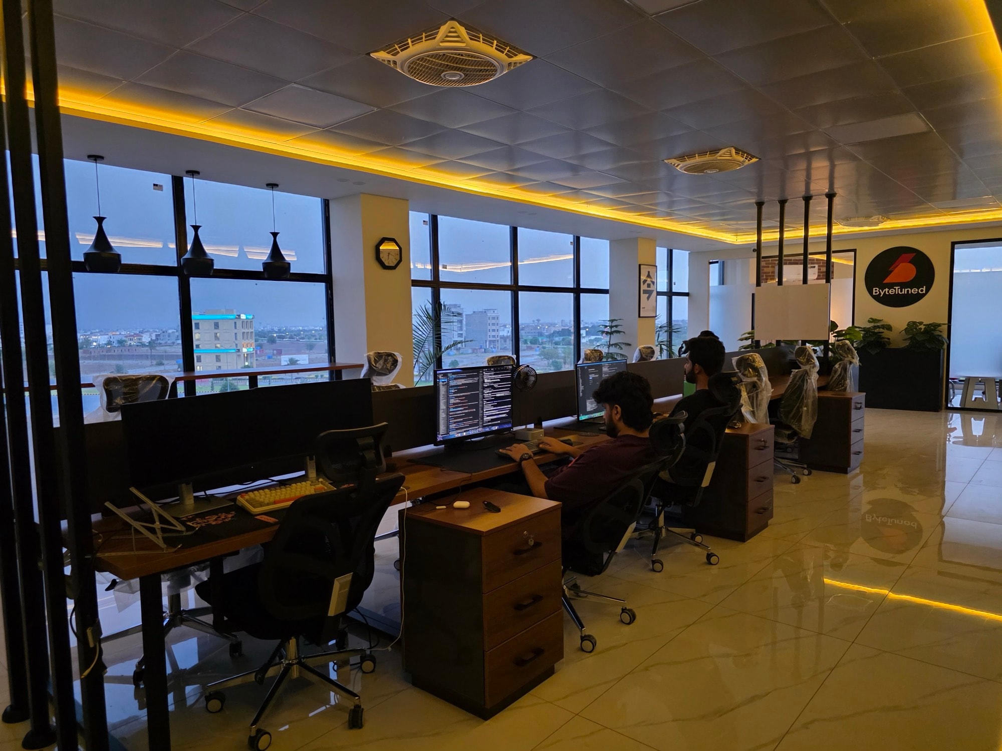 ByteTuned engineers at work on the open-plan engineering floor, city view at dusk